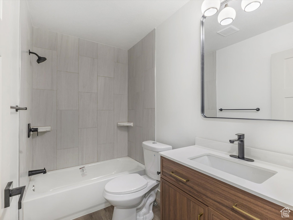 Full bathroom featuring hardwood / wood-style flooring, toilet, vanity, and tiled shower / bath