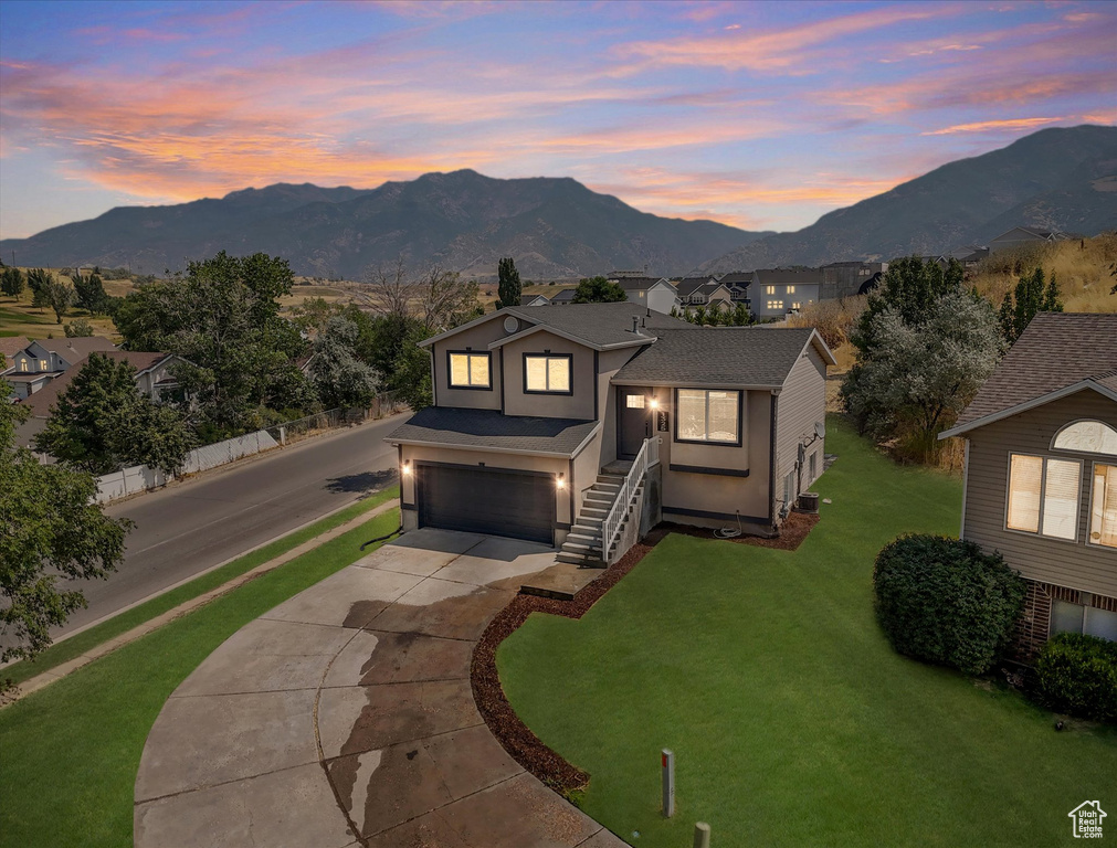 View of front of house with a garage, a yard, and a mountain view