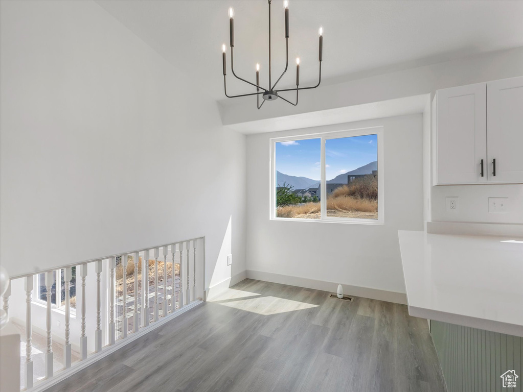 Unfurnished dining area featuring light hardwood / wood-style flooring and an inviting chandelier