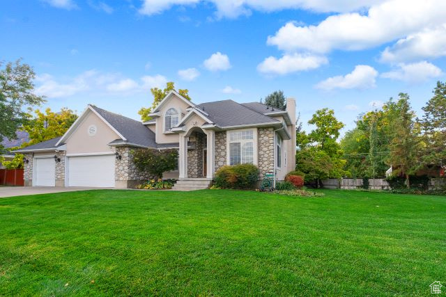 View of front of property with a garage and a front lawn