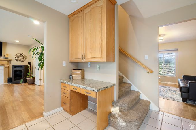 Kitchen with built in desk, light stone countertops, and light hardwood / wood-style flooring