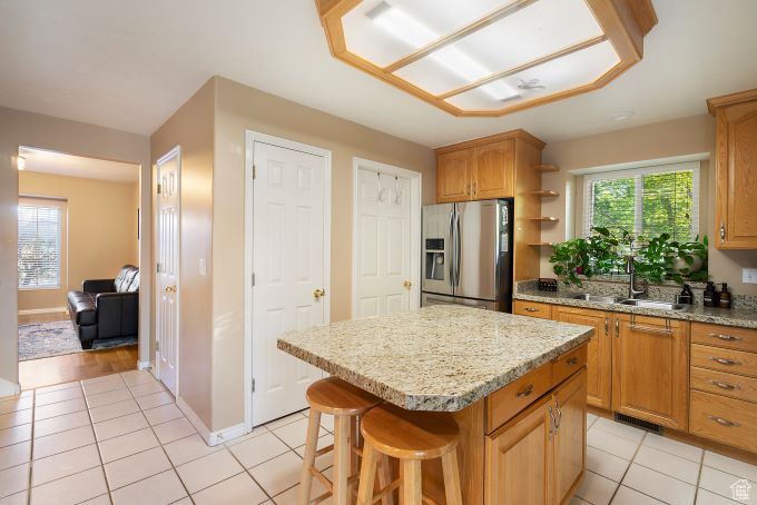 Kitchen featuring stainless steel fridge with ice dispenser, light hardwood / wood-style flooring, a center island, a kitchen breakfast bar, and sink