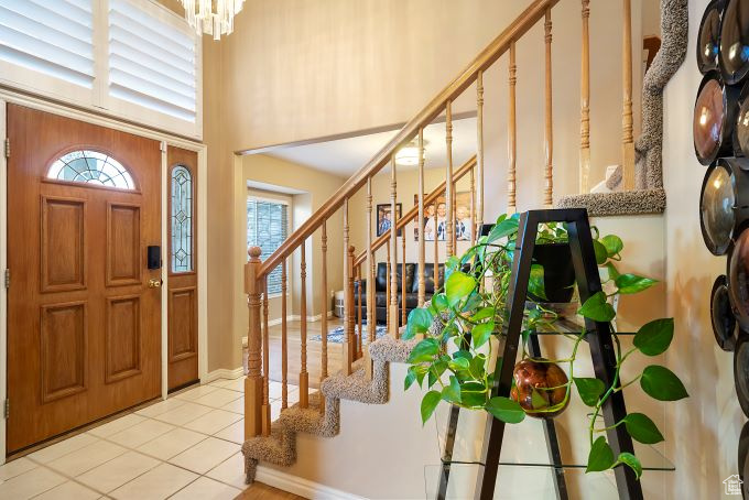 Foyer with light tile patterned flooring, a high ceiling, and a notable chandelier