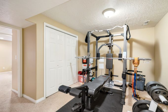 Exercise room featuring light carpet and a textured ceiling