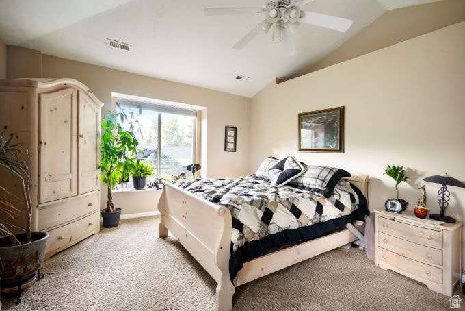 Bedroom featuring ceiling fan, vaulted ceiling, and light colored carpet