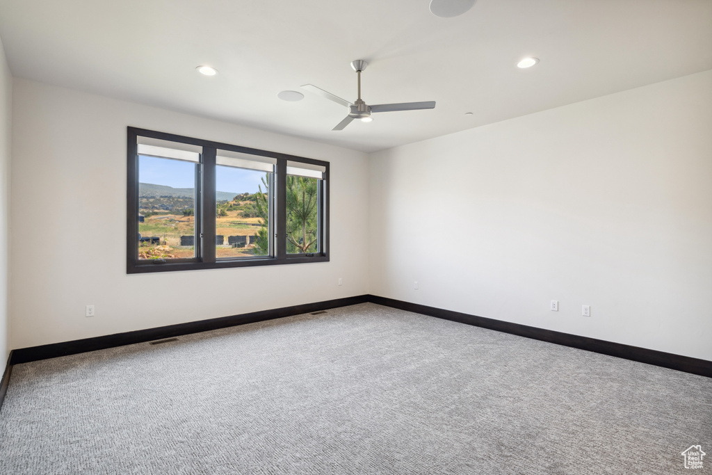 Spare room featuring carpet and ceiling fan