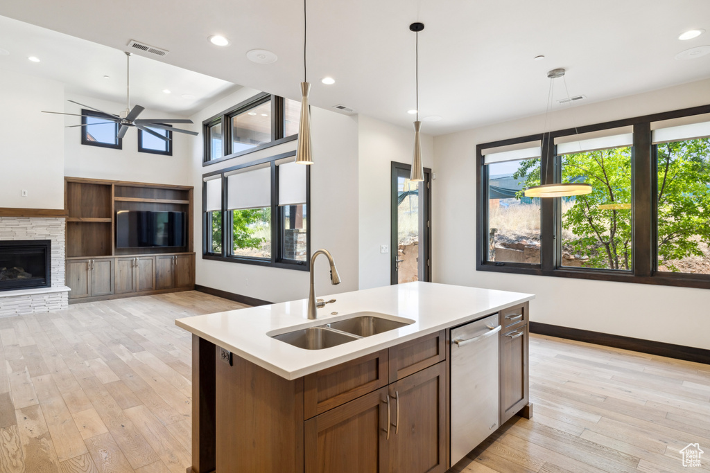 Kitchen featuring a fireplace, a healthy amount of sunlight, a kitchen island with sink, and dishwasher