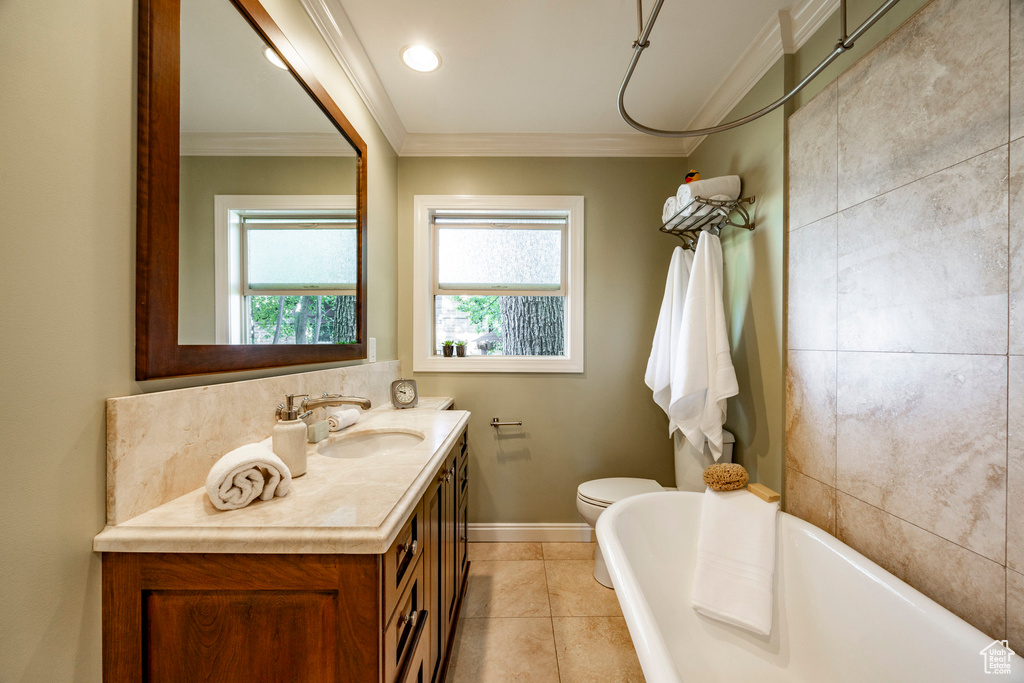 Bathroom with tile walls, tile patterned flooring, vanity, crown molding, and toilet