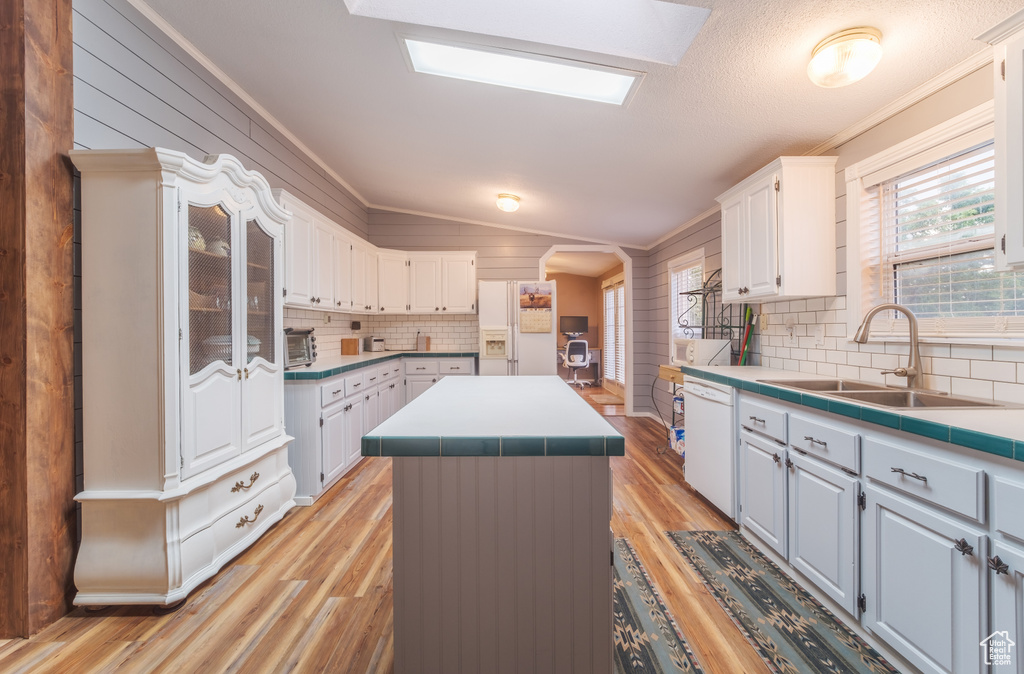 Kitchen featuring crown molding, white appliances, a center island, backsplash, and sink