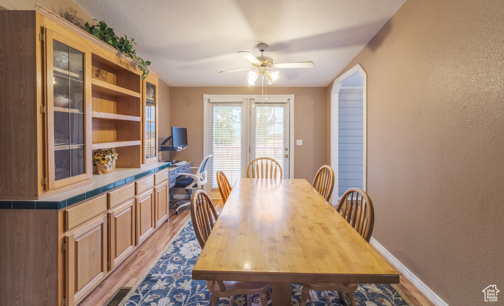 Dining room featuring light hardwood / wood-style flooring, a textured ceiling, and ceiling fan