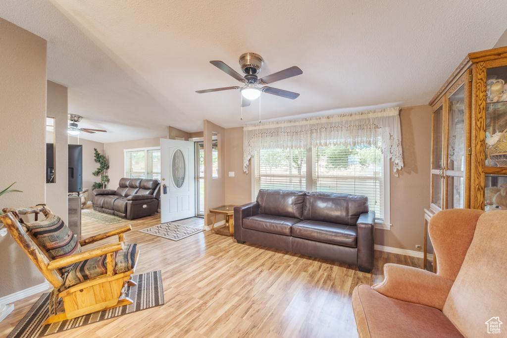 Living room with plenty of natural light, light hardwood / wood-style floors, and ceiling fan