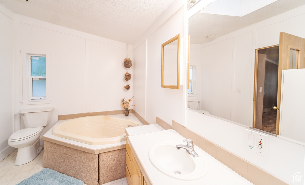 Bathroom with vanity, toilet, tile patterned floors, and a tub to relax in