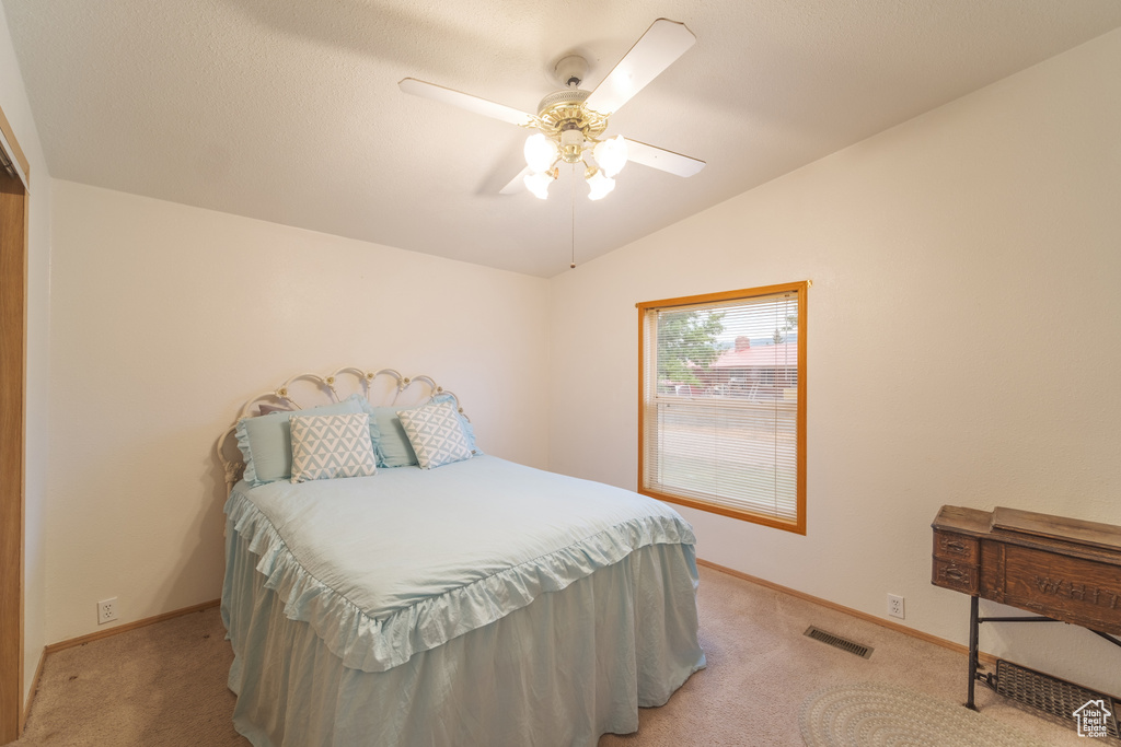 Carpeted bedroom with vaulted ceiling and ceiling fan