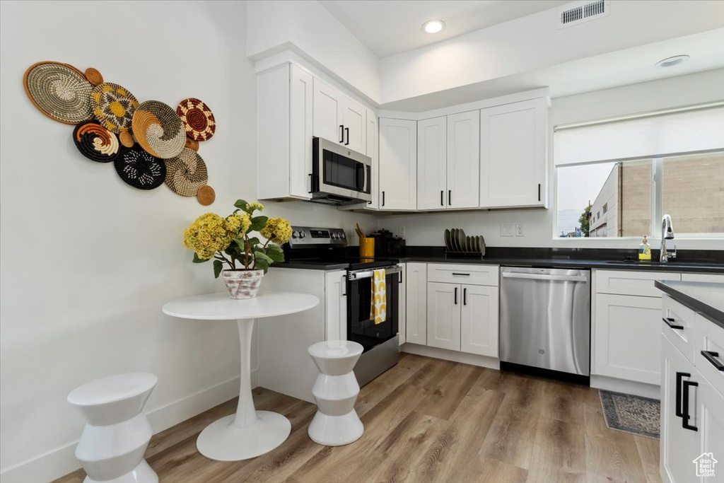 Kitchen featuring light hardwood / wood-style flooring, white cabinetry, appliances with stainless steel finishes, and sink