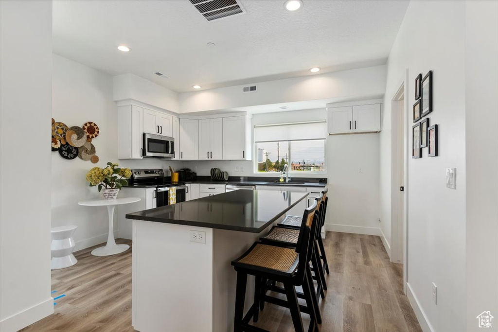 Kitchen featuring light wood-type flooring, white cabinetry, and appliances with stainless steel finishes