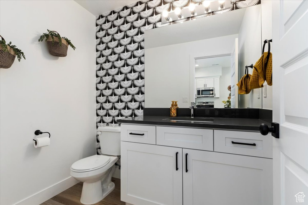 Bathroom featuring hardwood / wood-style flooring, vanity, and toilet