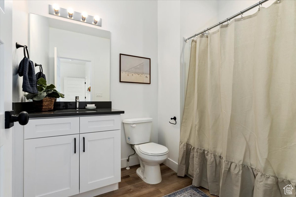 Bathroom with wood-type flooring, vanity, and toilet