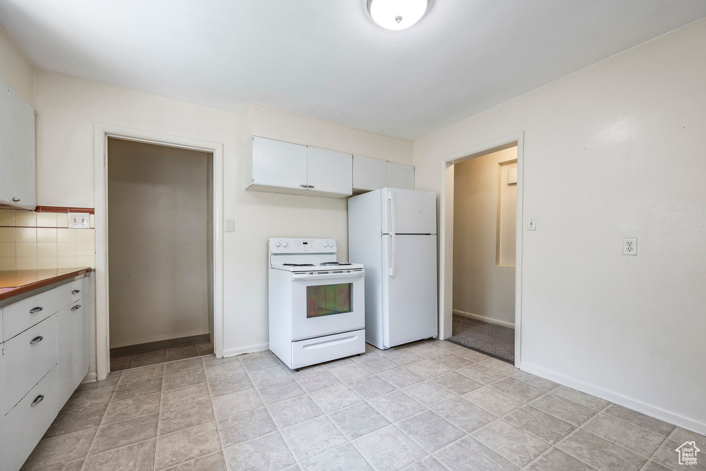 Kitchen featuring white cabinetry, white appliances, butcher block counters, light tile patterned floors, and backsplash