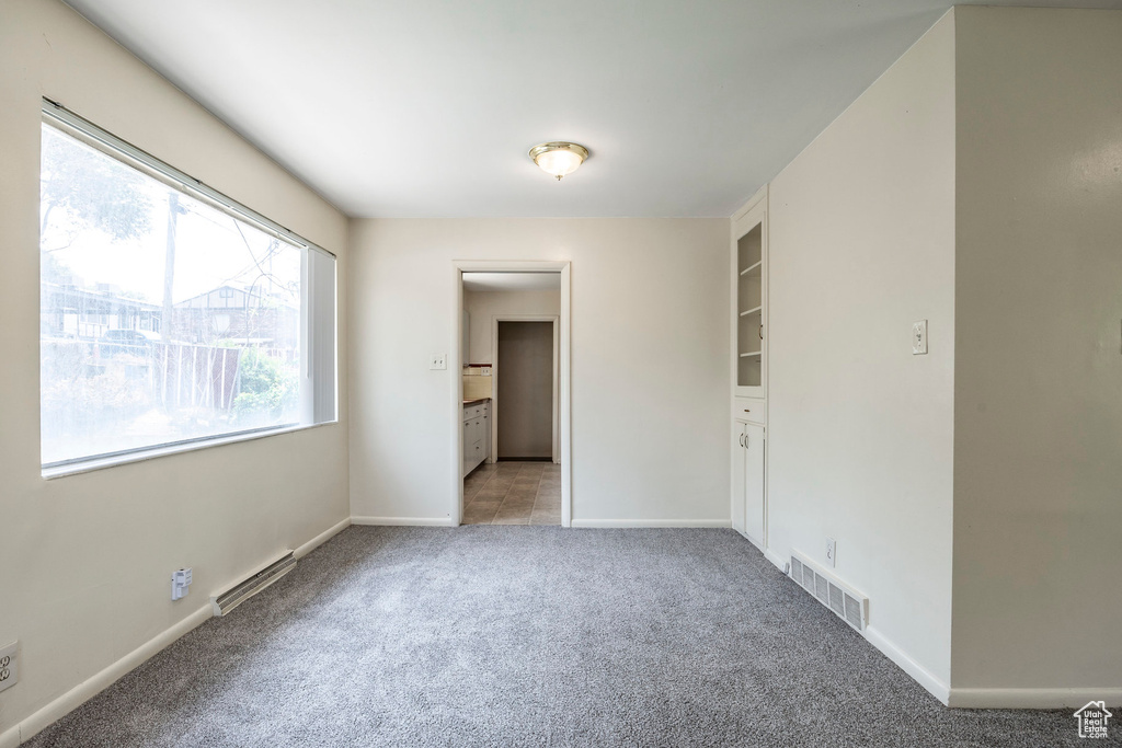 Unfurnished bedroom featuring ensuite bathroom and light carpet