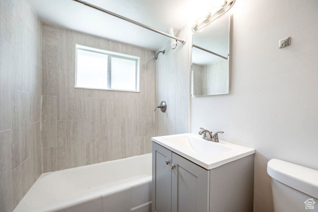 Full bathroom featuring vanity, tiled shower / bath combo, and toilet