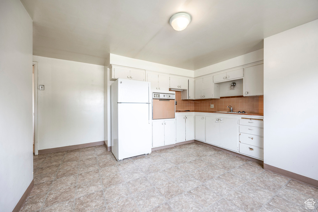 Kitchen with light tile patterned flooring, tasteful backsplash, white refrigerator, wall oven, and sink