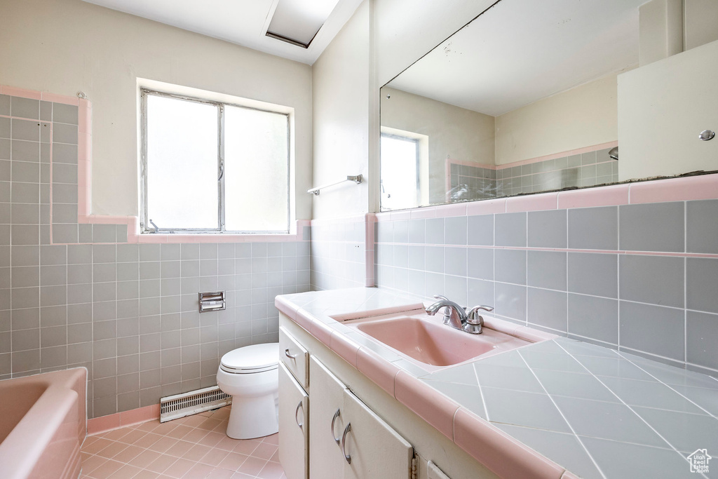 Full bathroom with tile patterned flooring, tile walls, and plenty of natural light