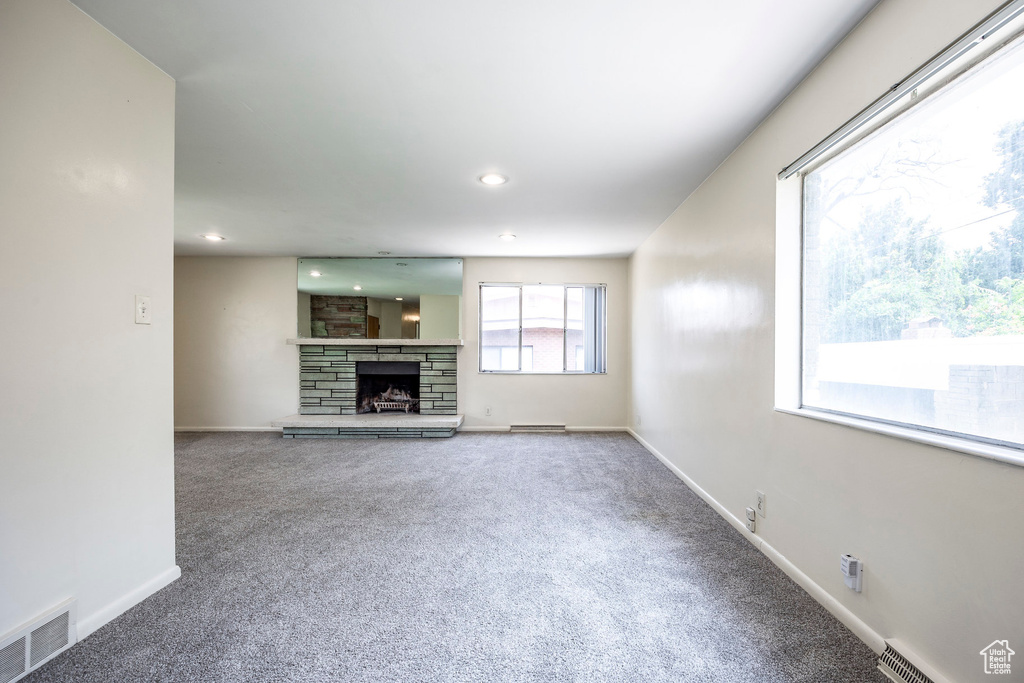 Unfurnished living room with carpet floors and a stone fireplace