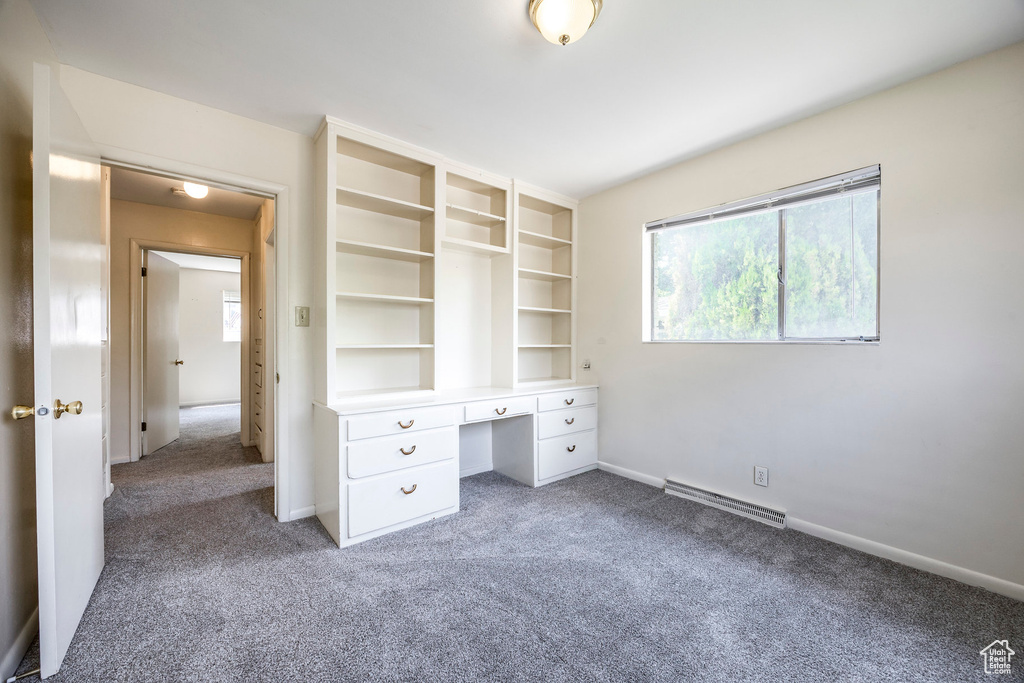 Unfurnished bedroom with a baseboard radiator, carpet, and built in desk