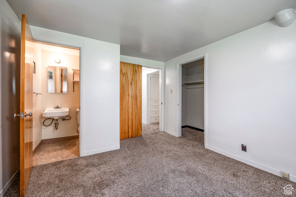 Unfurnished bedroom with ensuite bath, sink, a closet, and carpet flooring