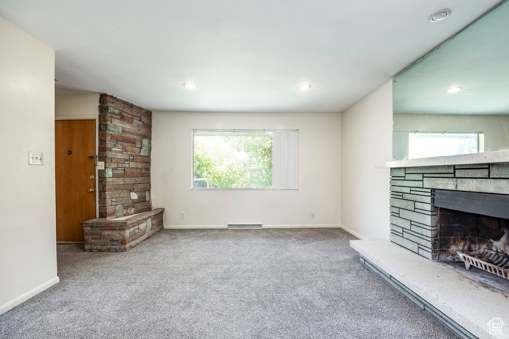 Unfurnished living room featuring a fireplace and carpet flooring