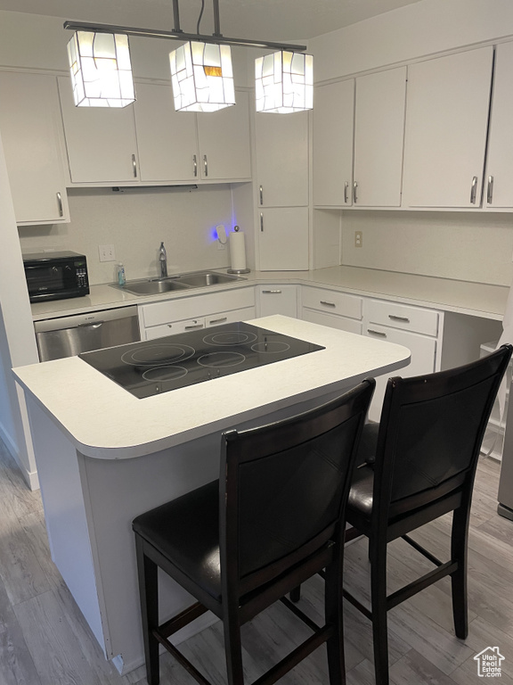 Kitchen with sink, light hardwood / wood-style flooring, and white cabinets