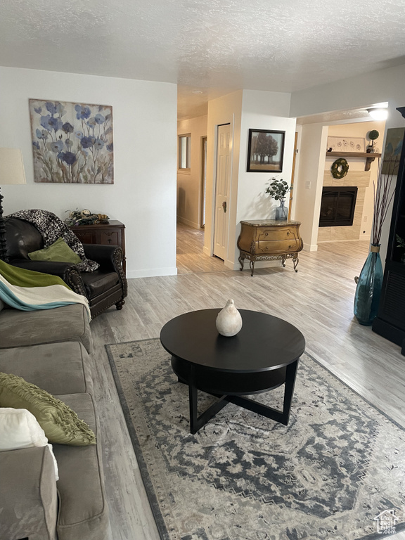 Living room with a tiled fireplace, light hardwood / wood-style flooring, and a textured ceiling