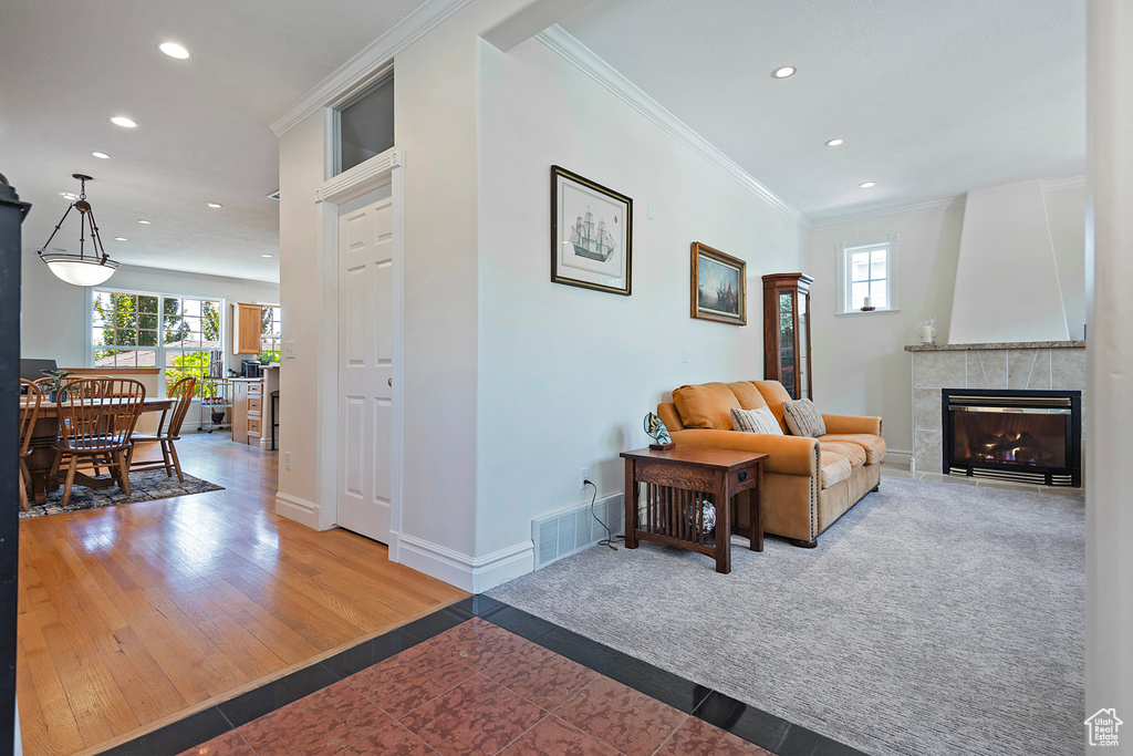 Living room with a fireplace, hardwood / wood-style flooring, and ornamental molding