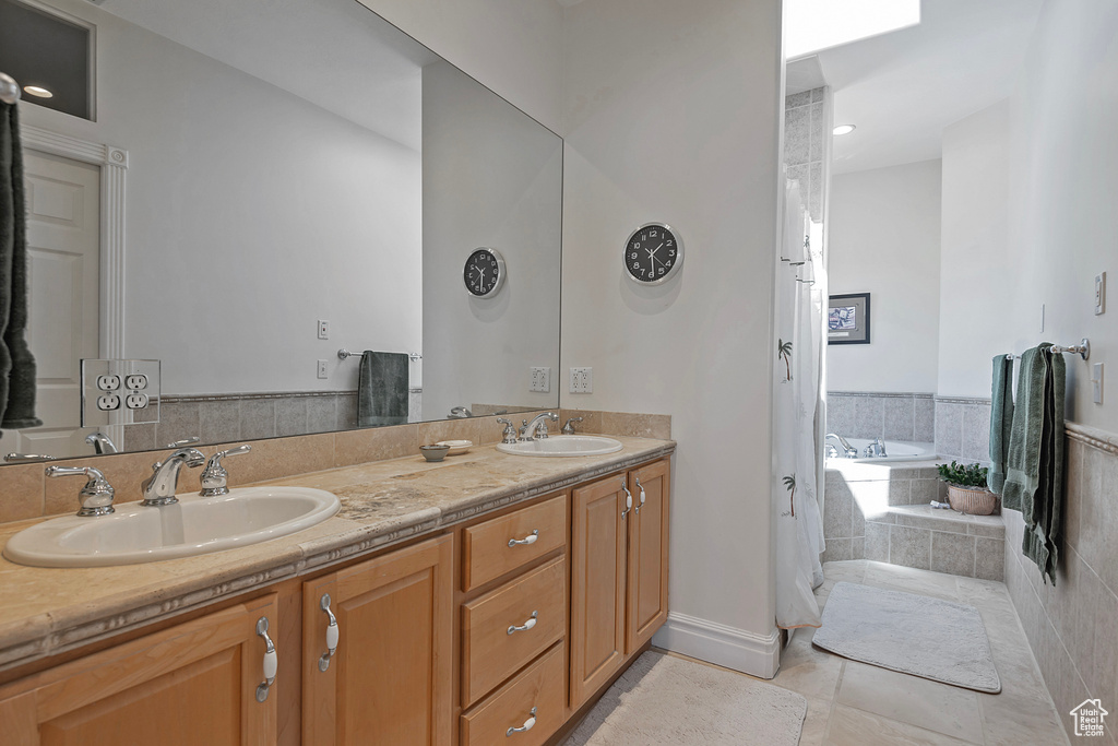 Bathroom with tiled tub, dual vanity, and tile patterned floors