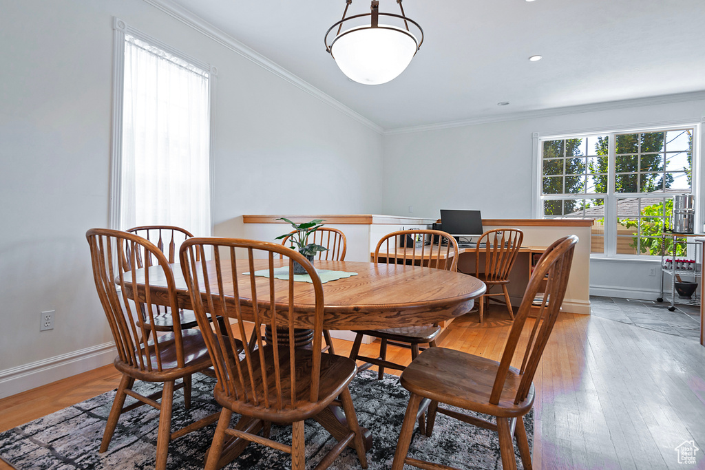 Dining space with light hardwood / wood-style flooring and crown molding