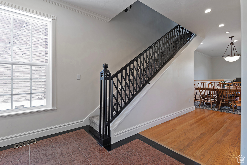 Stairs with wood-type flooring and crown molding