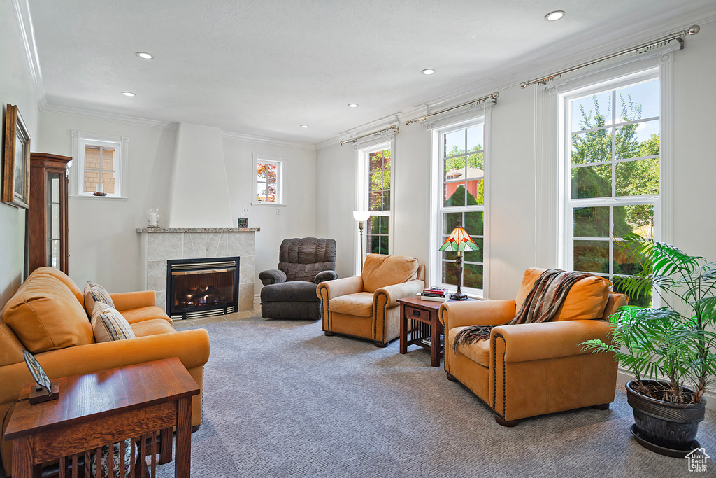 Living room with ornamental molding, carpet floors, and a tiled fireplace