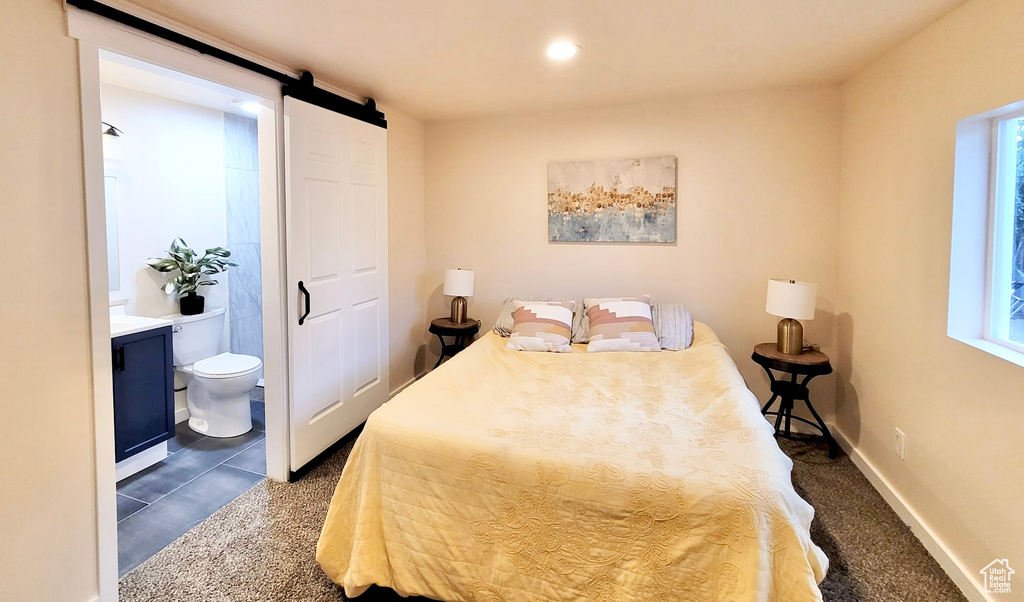 Tiled bedroom featuring ensuite bathroom, multiple windows, and a barn door