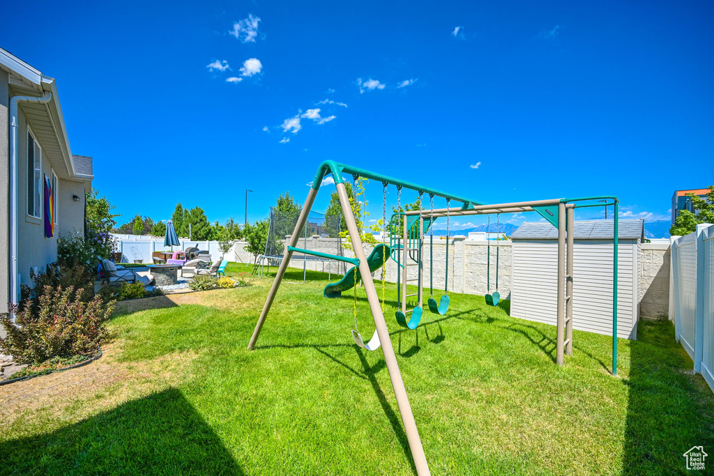 View of playground with a shed, a lawn, and a patio area