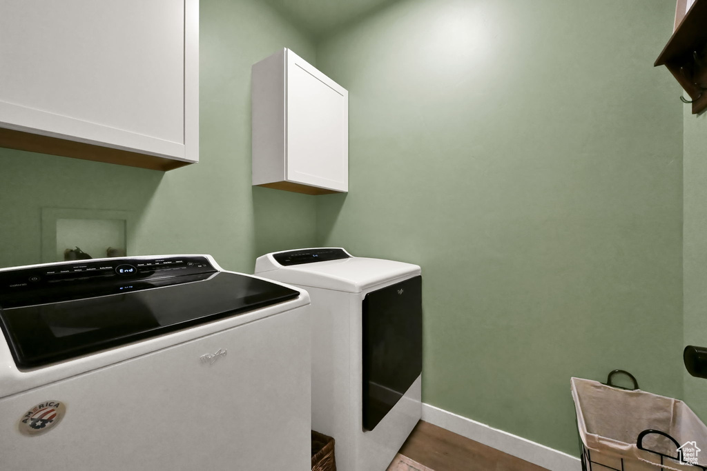 Clothes washing area with light hardwood / wood-style floors, cabinets, and washer and clothes dryer