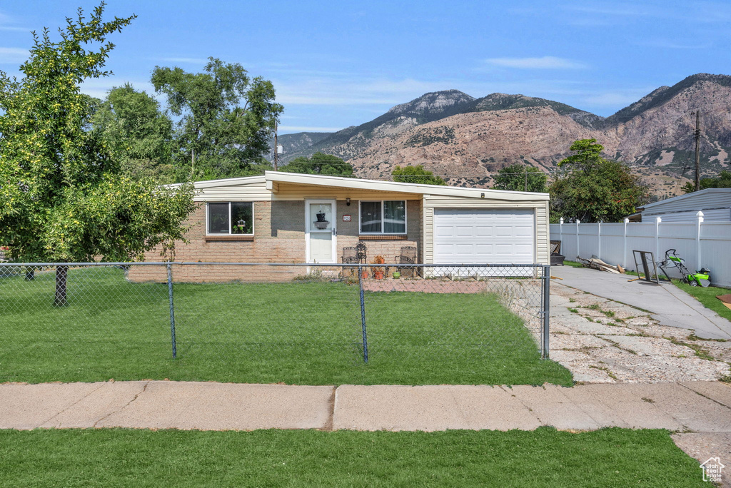 Ranch-style house featuring a garage, a mountain view, and a front lawn