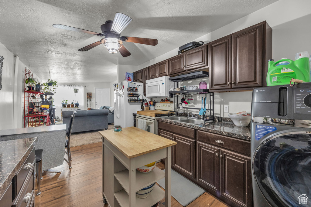 Kitchen featuring dark brown cabinets, light hardwood / wood-style flooring, stacked washer and dryer, and white appliances