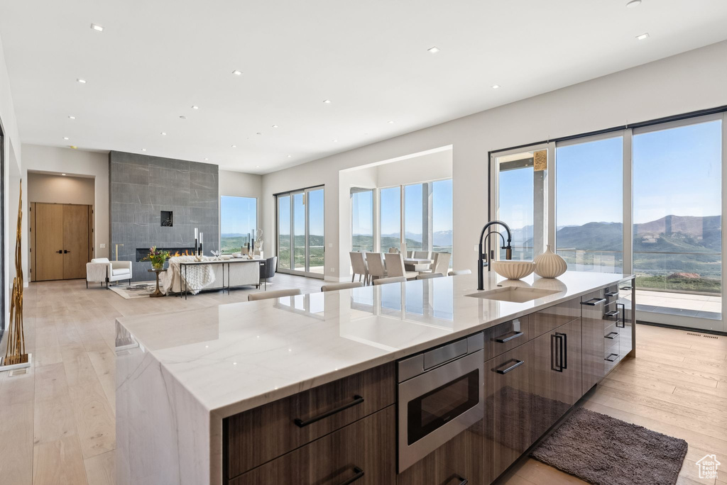 Kitchen with modern cabinets, stainless steel microwave, a large island with sink, light wood-style floors, and recessed lighting