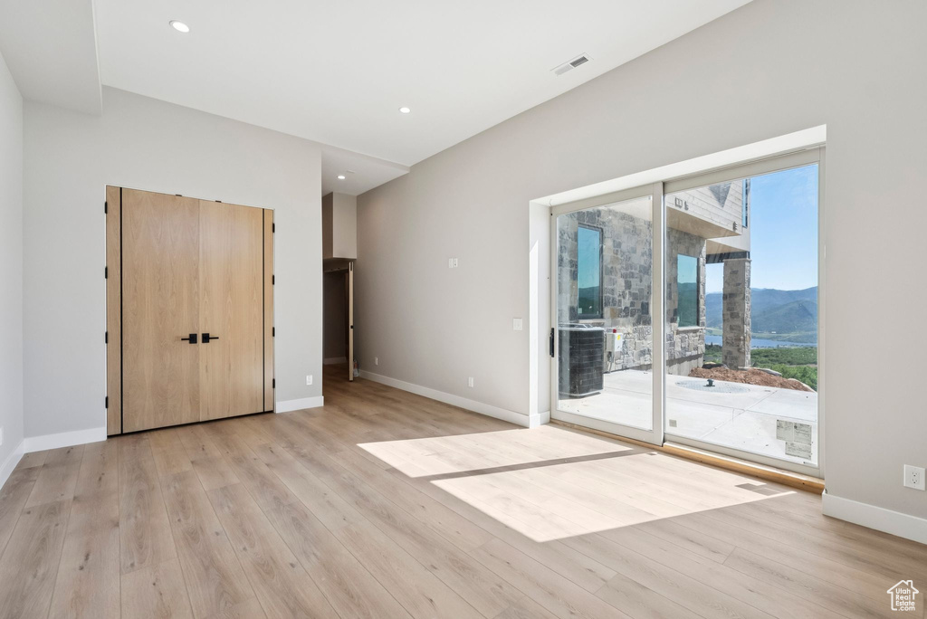Unfurnished bedroom featuring access to exterior, light wood-type flooring, a mountain view, and recessed lighting