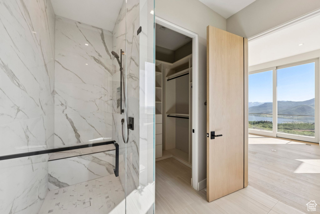 Full bath with a marble finish shower, a walk in closet, and a water and mountain view