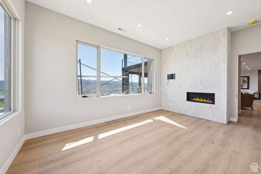 Unfurnished living room with light wood-style flooring, recessed lighting, and a large fireplace