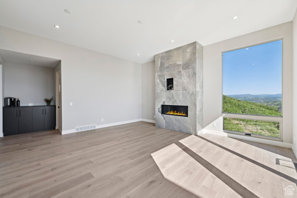 Unfurnished living room with light wood-style flooring, a fireplace, and recessed lighting
