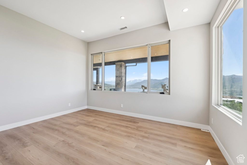 Unfurnished room with light wood-style floors, a mountain view, and recessed lighting