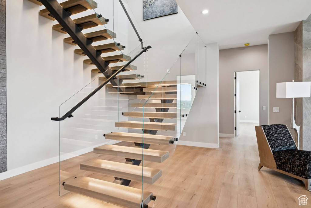 Staircase with wood finished floors and recessed lighting