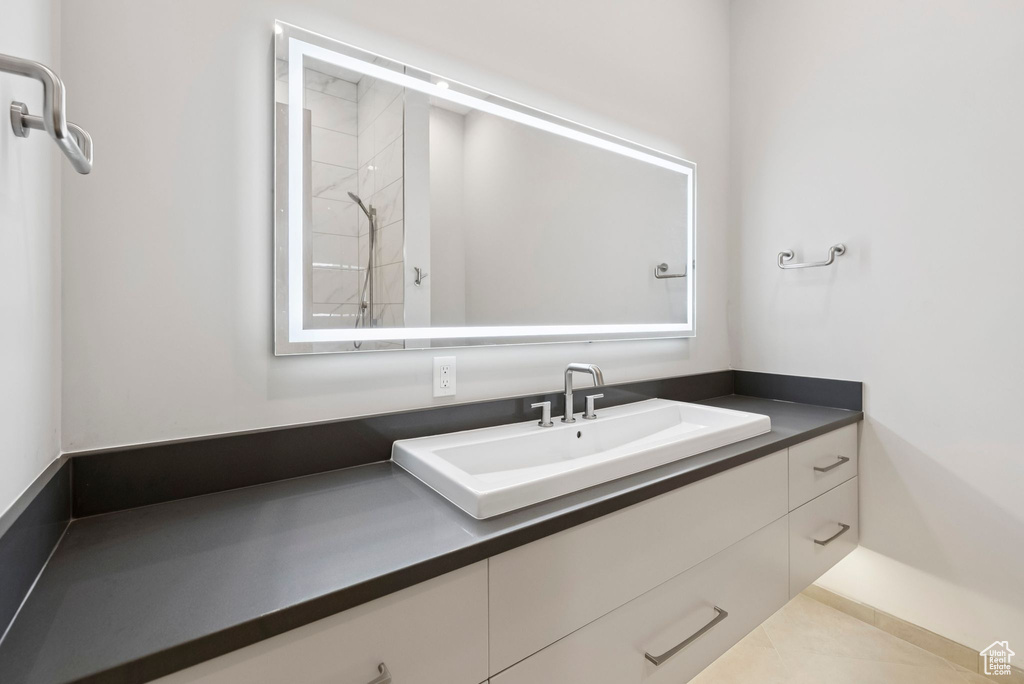 Bathroom with vanity, tiled shower, and tile patterned flooring